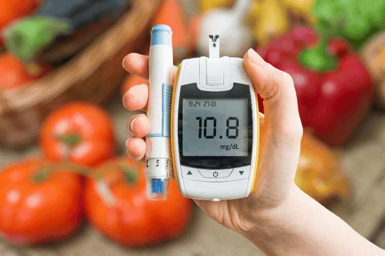 A hand holding glucometer and a healthy diet for diabetes in the background A hand holding glucometer and a healthy diet for diabetes in the background